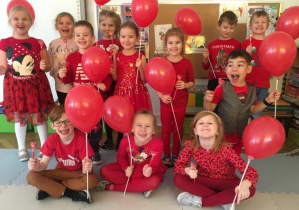 Dzieci pozują do zdjęcia trzymając czerwone balony